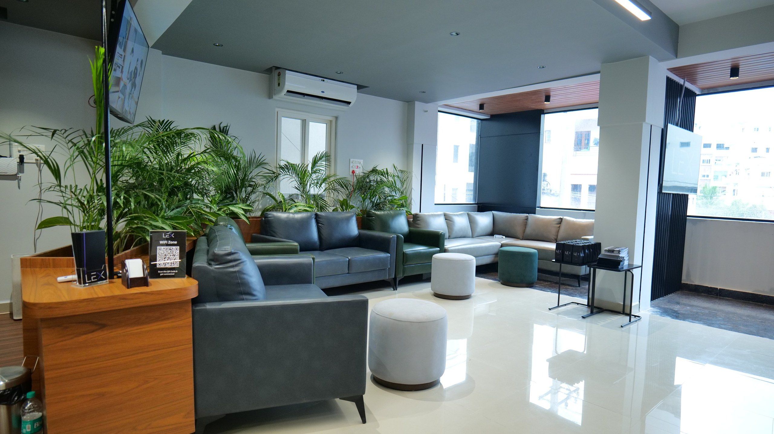 LeX lounge interior with leather sofas, potted palms and a wooden reception counter